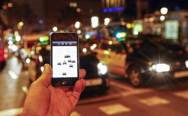Un hombre sostiene un smartphone en un paso de peatones.