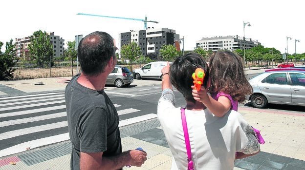 Óscar y Leticia, con Zhoe en brazos, señalan una grúa -la única tras el estallido de la burbuja inmobiliaria y la crisis económica que se ve en todo el barrio-.