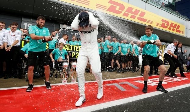 El británico Lewis Hamilton recibe la tradicional ducha de champán por parte de sus auxiliares en Mercedes. :: Andrew Boyers / REUTERS