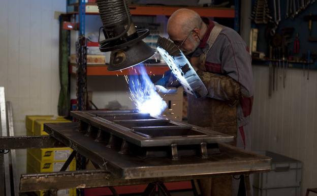 Un trabajador suelda unas piezas en el taller.