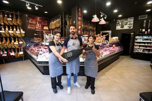 David Fernández, en el centro, junto con dos trabajadoras de Jamones Galilea, en la tienda de Jorge Vigón. :: /Juan Marín