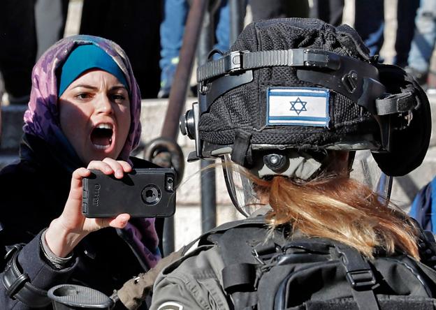 Dos jóvenes palestinos discuten con una agente de las fuerzas de seguridad israelíes. :: THOMAS COEX / afP/